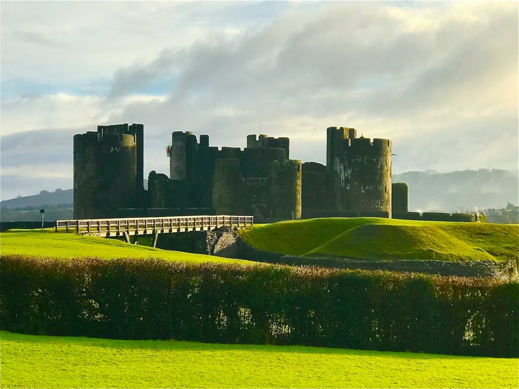 green grass field near castle under white clouds during daytime