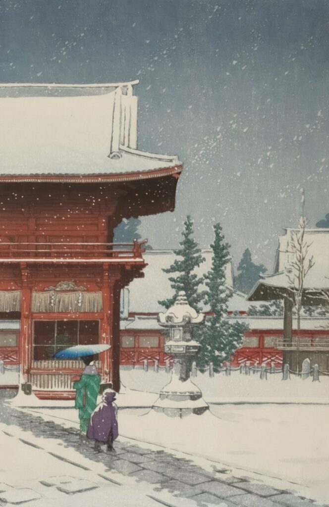 Two people walk in the snow near a red temple.